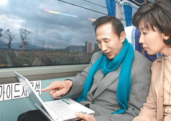 한나라당 이명박 후보가 30일 제주 유세를 위해 김포공항으로 이동하는 버스 안에서 나경원 대변인에게서 유세 관련 보고를 받고 있다. 이종승 기자