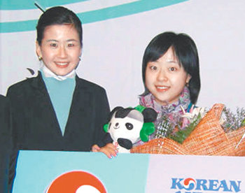 조수진 씨(오른쪽)가 새해 첫 손님에게 주는 왕복항공권과 베이징 올림픽 마스코트 인형을 선물 받고 있다. 사진 제공 대한항공