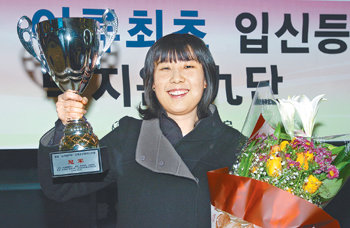 국내 여성기사 최초로 9단으로 승단한 박지은 씨가 18일 중국 베이징에서 귀국한 직후 인천공항에서 환영객들이 건넨 꽃다발 등을 들고 활짝 웃고 있다. 사진 제공 월간바둑