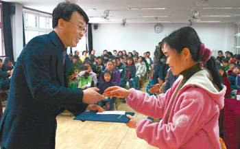 28일 충북 제천시 봉양초교 학교마을도서관 개관식에서 ‘푸름이닷컴’의 최희수 대표(왼쪽)가 개관식 기념 백일장에서 입상한 주민에게 상과 부상을 시상했다. 제천=정양환  기자