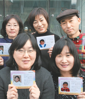 사진작가 이겸 씨(뒷줄 오른쪽)가 ‘밝은 벗’ 회원들과 함께 볼리비아 후원 아동들의 사진을 꺼내 보여 주고 있다. 사진 제공 월드비전