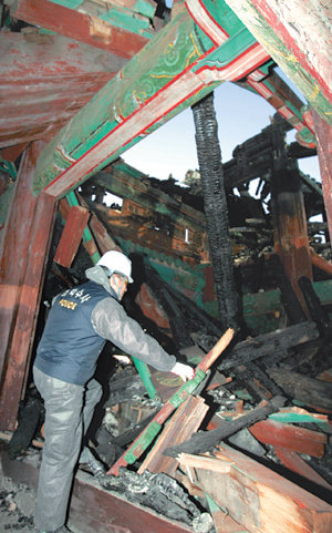 처참한 현장화재로 전소된 숭례문 내부가 13일 공개됐다. 경찰 감식반원이 타다 남은 목재더미를 살펴보고 있다. 전영한  기자