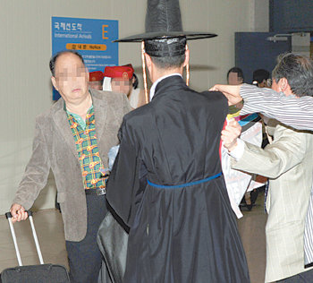 정부는 앞으로 엄격한 심사를 통해 공공기관 임직원의 외유성 해외 출장을 막기로 했다. 지난해 5월 남미로 외유성 출장을 떠났던 한 공기업의 감사가 인천공항을 통해 입국하던 중 암행어사 복장을 한 시민단체 관계자가 미꾸라지를 뿌려 당황하는 모습. 동아일보 자료 사진