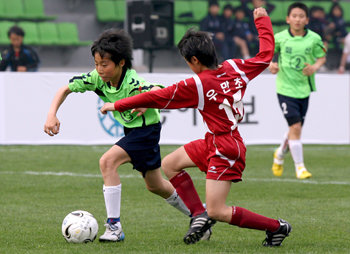 전국 216개 초등학교 축구팀이 참가하는 국내 최대 규모의 유소년 축구리그인 동원컵대회가 16일 개막했다. 개막전에서 화산초교 한기재(왼쪽)가 우만초교 수비수를 제치고 공을 몰고 있다. 수원=홍진환 기자