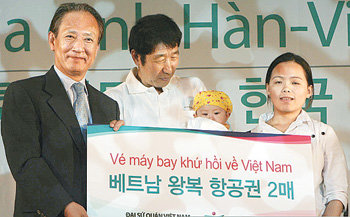 하나금융그룹 김승유 회장(왼쪽)이 25일 충북 충주시 동량면 하천리 충주호리조트에서 열린 ‘제3회 베트남-한국 가족의 날’ 행사에서 베트남 왕복 항공권을 결혼이주여성 가족에게 전달하고 있다. 사진 제공 하나금융지주