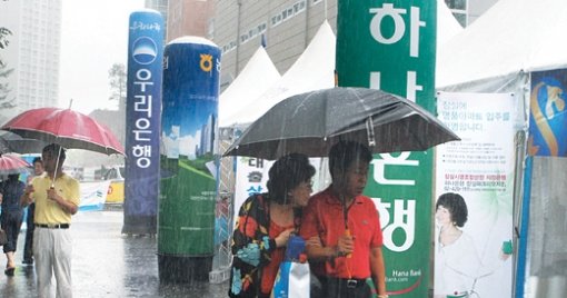 ‘떴다방 은행.’ 19일 서울 송파구 신천동 잠실파크리오 단지 입구에 ‘떴다방(이동식 부동산 중개업체)’을 연상시키는 은행 임시 대출상담센터가 줄지어 서 있다. 은행 직원들은 폭우 속에서도 입주할 아파트를 보러 온 사람들을 대상으로 대출상품 등을 경쟁적으로 홍보했다. 사진 제공 하나은행