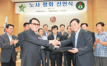 롯데칠성 노사 대표와 임직원들은 31일 서울 서초구 잠원동 본사에서 ‘노사평화 선언식’을 열었다. 정황(앞줄 왼쪽) 롯데칠성 대표이사 부사장과 이영철 노조위원장이 노사평화 협정서를 교환하며 악수하고 있다. 사진 제공 롯데칠성