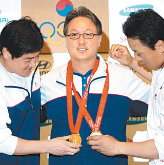 야구 대표팀 주장 진갑용(왼쪽)과 4번 타자 이승엽(오른쪽)이 24일 중국 베이징 시내 코리아하우스에서 열린 기자회견 때 김경문 감독에게 자신이 받은 금메달을 걸어주고 있다. 베이징=올림픽사진공동취재단