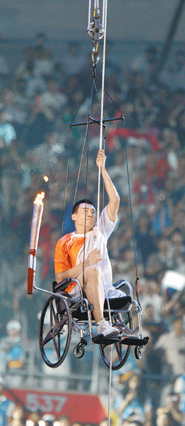 6일 중국 베이징의 올림픽 주경기장에서 개최된 장애인올림픽 개회식에서 높이뛰기 선수인 허우빈이 성화 점화를 위해 밧줄을 손으로 잡아당기며 성화대로 올라가고 있다. 베이징=로이터 연합뉴스