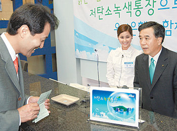 지난달 22일 오세훈 서울시장(왼쪽)이 우리은행의 ‘저탄소 녹색통장’에 1호로 가입하고 있다. 오른쪽은 이날 일일창구직원으로 활동한 우리은행 이종휘 행장. 사진 제공 우리은행