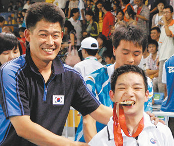 금메달을 목에 건 박건우(오른쪽)가 김진한 코치와 함께 시상식을 마친 뒤 금메달을 깨물어보고 있다. 베이징=연합뉴스