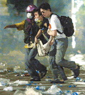 7일 태국 방콕의 국회의사당 부근에서 경찰이 반정부 시위대를 해산시키기 위해 최루탄을 쏘자 시위 참가자들이 부상한 것으로 보이는 동료를 부축해 뛰어가고 있다. 경찰과 시위대 간 충돌로 2명이 숨지고 400여 명이 부상했다. 방콕=로이터 연합뉴스