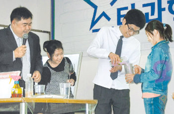 최정훈 교수(왼쪽)가 ‘스타과학자와 함께하는 나의 미래’ 강연회에 참석한 청소년들과 함께 비커에 담긴 액체의 색깔을 다양하게 바꾸는 실험을 하며 첨단과학에 대해 설명하고 있다. 대구=김상연 동아사이언스  기자