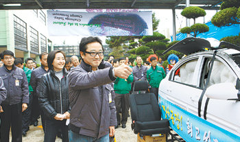 이웅열 코오롱그룹 회장(가운데)이 지난달 31일 경북 구미시 공단동 ㈜코오롱 구미공장을 방문해 에어백 성능을 시연하는 장면을 지켜보면서 엄지손가락을 치켜들고 있다. 이 회장은 이날 부인 서창희 씨(이 회장 뒤쪽)와 함께 회사 동계 잠바를 입고 나와 직원들과 일체감을 나타냈다. 사진 제공 코오롱