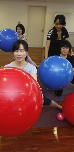 석화숙 씨(앞)가 백화점 문화센터에서 어머니 채순자 씨(오른쪽)와 함께 커다란 고무공을 들고 필라테스 운동을 하고 있다. 김현아 강사가 채 씨의 자세를 바로잡아 주고 있다. 이훈구 기자