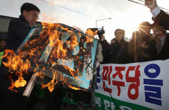 자유북한운동연합 등 탈북자단체와 보수 시민단체 회원 120여명이 28일 서울 영등포구 민주당 당사 앞에서 민주당 대변인의 매국노 발언 관련 사과를 요구하며 준비한 피켓을 불태우고 있다. 연합