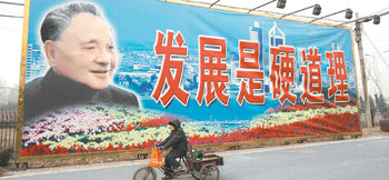 9일 중국 베이징에서 자전거를 탄 한 여성이 개방을 주도한 지도자 덩샤오핑의 초상이 담긴 대형 현수막 앞을 지나고 있다. 이 현수막에는 ‘발전은 확고한 원칙’이라는 문구가 적혀 있다. 이달 개방 30주년을 맞은 중국은 세계 4대 경제권으로 부상했다. 베이징=로이터 연합뉴스