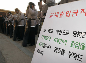 22일 서울 송파초등학교 교문에서 경찰이 학부모와 외부인 출입을 금지하는 팻말을 세우고 경비를 하고 있다. 학력평가 시험 거부를 유도했다는 이유로 해고된 이 학교 박수영 전 교사는 이날 학생 20여 명과 함께 학교 앞에서 야외수업을 했다. 연합뉴스