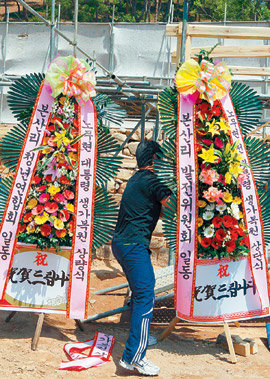 ‘前 대통령’서 ‘노무현 대통령’으로 리본 교체 4일 오후 경남 김해시 진영읍 봉하마을에서 열린 노무현 전 대통령 생가복원 상량식을 앞두고 행사 관계자가 화환 리본을 ‘노무현 전 대통령’이라고 적힌 것에서 ‘노무현 대통령’이라고 적힌 것으로 서둘러 바꿔 달고 있다. 김해=연합뉴스