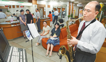 1일 오후 서울 송파우체국에서 한병수 우체국장(오른쪽)이 색소폰을 연주하고 있다. 송파우체국은 한 씨가 부임한 뒤 미니 콘서트와 미용봉사, 의료봉사가 매주 이어지며 지역 주민들에게 ‘열린 공간’으로 다가서고 있다. 김재명 기자