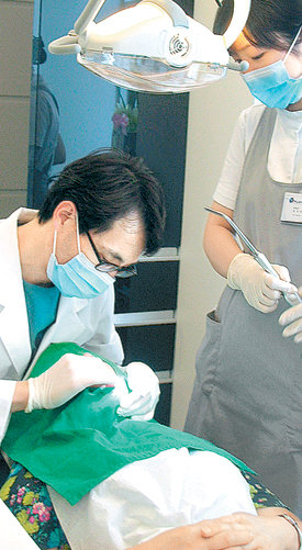 치아 건강을 위해서는 올바른 칫솔질 외에도 주기적인 치아 검진이 필요하다. 치과 의사가 환자의 치아 상태를 확인하기 위해 치아를 살펴보고 있다. 동아일보 자료 사진
