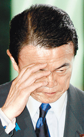 일본 도쿄도의회 선거에서 참패한 집권여당의 아소 다로 일본 총리가 13일 기자회견에 앞서 착잡한 표정을 지으며 손을 들어 인사하고 있다. 도쿄=AP 연합뉴스