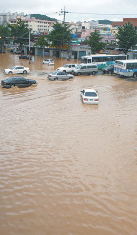 국지성 폭우로 부산 지역 일부 도로가 물에 잠겼다. 16일 부산 남구 대연동의 한 교차로에서 차량들이 흙탕물을 뚫고 서행하고 있다. 부산=연합뉴스