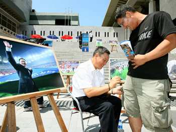 “축구 많이 사랑해주세요.” 허정무 축구대표팀 감독(왼쪽)이 5일 서울 세종문화회관 앞에서 열린 7회 연속 월드컵 본선 진출 기념 사진전에서 한 팬의 반바지에 사인을 해주며 활짝 웃고 있다. 40점이 출품된 사진전은 7일까지 계속되며 11일 청계광장에서 열린 뒤 12일 한국과 파라과이의 평가전 때 추첨을 통해 팬들에게 나눠준다. 연합뉴스