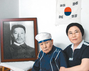 안중근 의사의 종질부인 안노길 할머니(왼쪽)가 중국 헤이룽장 성 하얼빈 자택에서 최선옥 수녀와 함께 앉아 회한에 잠겨 있다. 뒤로는 안 의사의 사진과 안 할머니가 손수 수놓아 만든 태극기가 보인다. 하얼빈=구자룡 특파원