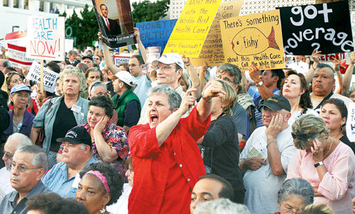 11일 미 캘리포니아 주 앨햄브라에서 열린 타운홀 미팅에서 건강보험 개혁에 반대하는 한 여성(가운데)이 손목시계를 가리키며 패널의 연설 중단을 거칠게 요구하고 있다. 앨햄브라=AP 연합뉴스