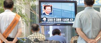 18일 오후 인천국제공항에서 여행객들과 공항 직원들이 김대중 전 대통령의 서거 소식을 전하는 TV 속보를 지켜보고 있다. 김 전 대통령은 이날 오후 1시 43분 서거했다. 인천=연합뉴스