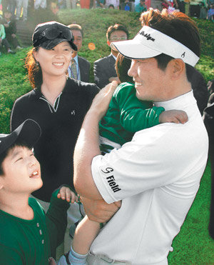 평소 가정적인 성격으로 유명한 양용은(오른쪽)이 2006 한국오픈에서 우승한 뒤 부인 박영주 씨가 지켜보는 가운데 막내아들을 끌어안고 있다. 사진 제공 JNA