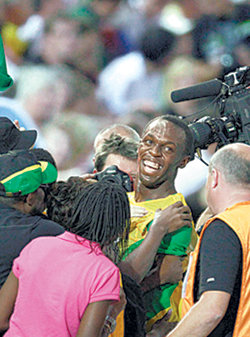 21일 베를린 세계육상선수권 남자 200m 결승에서 세계신기록(19초19)을 세운 자메이카의 우사인 볼트(가운데)가 경기 직후 취재기자들에게 둘러싸인 채 환하게 미소 짓고 있다. 베를린=AP 연합뉴스