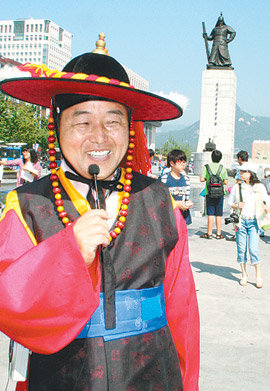 18일 첫선을 보인 서울 광화문광장의 ‘전기수’ 이익수 씨가 포도대장 복장을 갖추고 청소년들에게 광장 내 시설물에 담긴 역사를 구수하게 설명해 주고 있다. 이동영 기자