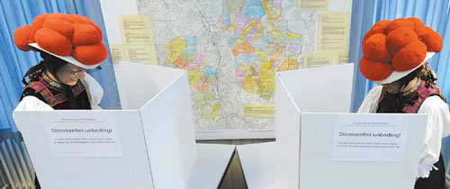 27일(현지 시간) 독일에서 총선거가 실시된 가운데 전통의상을 입은 두 여인이 호른베르크 레이첸바흐 지역의 투표소에서 기표를 하고 있다. 이번 총선에서는 29개의 정당이 598석의 하원의석을 놓고 치열한 승부전을 펼쳤다. 호른베르크 레이첸바흐=AP 연합뉴스