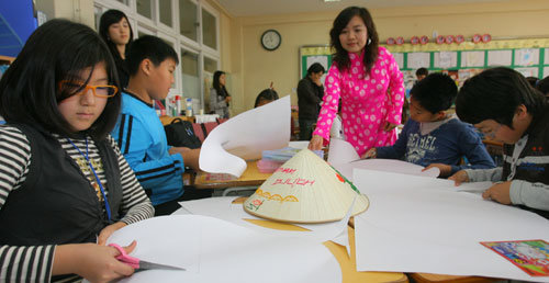 다문화전문강사 베트남인 유티미아 씨(오른쪽에서 세 번째)가 지켜보는 가운데 창도초등학교 5학년 4반 아이들이 도화지를 이용해 베트남 전통모자인 ‘논라’를 만들고 있다. 원대연 기자