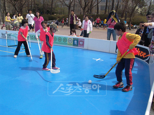 플로어볼은 편한 운동복 차림에 스틱과 볼 골대만 준비하면 공간의 제약 없이 남녀노소 누구나 쉽게 즐길 수 있는 종목이다. 초등학생들이 야외에서 미니 플로어볼 게임을 즐기고 있다. 사진제공 ｜ 국민생활체육회