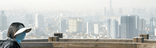 이달 21일 서울 남산 전망대에 오른 한 시민이 코와 입을 가린 채 황사로 뿌옇게 변한 도심 하늘을 바라보고 있다. 가을 황사는 한 번 발생하면 잘 날아가지 않고 머물러 있는 경우가 많아 주의가 필요하다. 동아일보 자료 사진