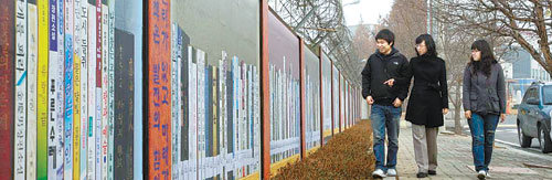 경북 칠곡군 주민들이 30일 왜관읍 칠곡군교육문화복지회관 출입 도로변 미군부대 담장에 꾸며진 ‘북로드’를 보면서 걷고 있다. 이
벽화는 회색빛 시멘트 담장을 색감이 살아있는 벽화로 단장해 도시 미관을 아름답게 꾸미고 문화예술도시로서 위상을 높이고자
설치했다. 사진 제공 칠곡군