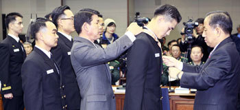 김태영 국방장관(오른쪽)이 9일 서울 용산구 국방부 청사에서 열린 전군 주요지휘관회의에서 대청해전에서 공을 세운 김상훈 대위에게 충무무공훈장을 수여 하고 있다. 이날 김 대위를 비롯한 대청해전 유공자 6명이 훈장을 받았다. 전영한 기자