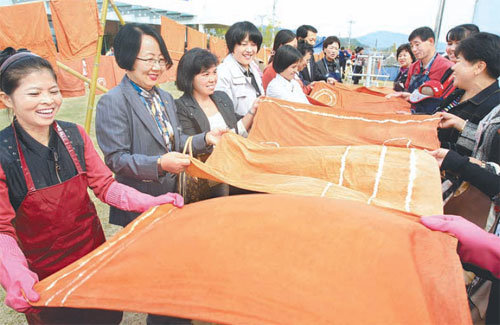 전남 나주시가 천연염색산업의 메카로 떠오르고 있다. 다시면 천연염색문화관에서 이주여성들과 결연을 맺은 여성들이 천연염색 체험에 나서 황토물을 들인 천을 마주잡고 말리고 있다. 동아일보 자료 사진