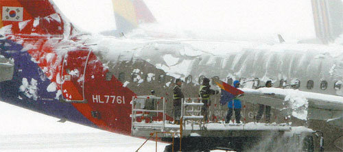 눈 맞고 주저앉은 항공기9년간 전면 중단 사태가 없었던 김포공항도 이번 폭설에는 어쩔 수 없었다. 4일 오전 관계자들이 운항 취소된 비행기 위에서 눈을 치우고 있다. 변영욱 기자
