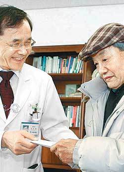 70년 전 아버지의 수술비를 뒤늦게 병원에 가져온 양치곤 씨(오른쪽)는 25일 병원 측에 “너무 늦어 죄송하다”고 미안해했다. 김민철 병원장은 “추운 날씨에 마음이 따뜻해지는 사연”이라며 건강검진권을 선물했다. 사진 제공 전주예수병원