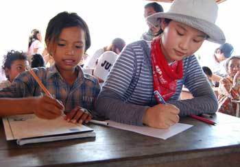 캄보디아의 농촌마을에서 자원봉사활동을 한 문다희 양(오른쪽)이 지난달 24일 꼭부릿 마을회관에서 똠 챈 띠아 양과 함께 서로에게 편지를 쓰고 있다. 사진 제공 굿네이버스