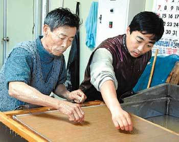 ‘문경 전통한지’를 만드는 김삼식 명장(왼쪽)과 아들 춘호 씨가 대나무발에 종이를 뜨면서 잡티를 없애고 있다. 이권효 기자