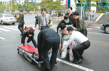 병원 옮겨지는 정 씨 검사에 대한 향응과 성 접대 의혹을 폭로한 건설업자 정모 씨가 23일 오후 2시 40분경 부산지법 앞 변호사 사무실에서 수면제를 다량 복용해 자살을 기도했다. 변호사 사무실과 119 관계자들이 의식을 잃은 정 씨를 병원으로 급히 옮기기 위해 휠체어에 탄 정 씨를 들것에 옮기고 있다. 부산=이종식 기자