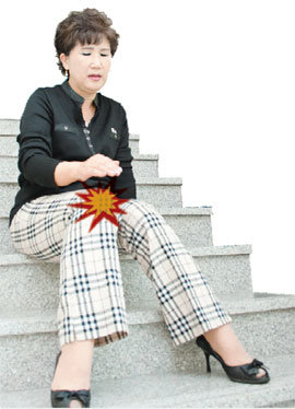 무릎 관절염을 앓고 있는 중년 여성이 계단을 내려오다 통증 때문에 앉아서 쉬고 있다. 사진 제공 힘찬병원