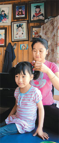 쿠엔킴풍 씨가 어린이집에 다니는 막내딸 등교 준비를 하고 있다. 뒤 벽면에 그가 키우는 네 아이의 어릴 적 사진이 걸려 있다. 울주=신광영 기자