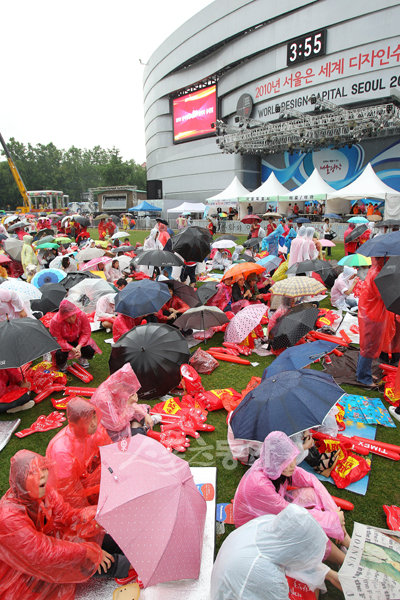 2010 남아공월드컵 그리스전이 열리는 12일 오후 서울시청 앞 광장에서 우비와 우산을 쓴 많은 시민들이 거리 응원을 펼치기 위해 자리를 잡고 있다. 국경원 기자 onecut@donga.com