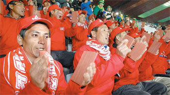 16일 오전 남아공 요하네스버그 엘리스파크 경기장에서 열린 G조 북한과 브라질의 경기에서 북한 남성 응원단 100여 명이 나무로 만든 응원 도구를 양손에 들고 소리를 내며 응원하고 있다. 요하네스버그=전영한 기자